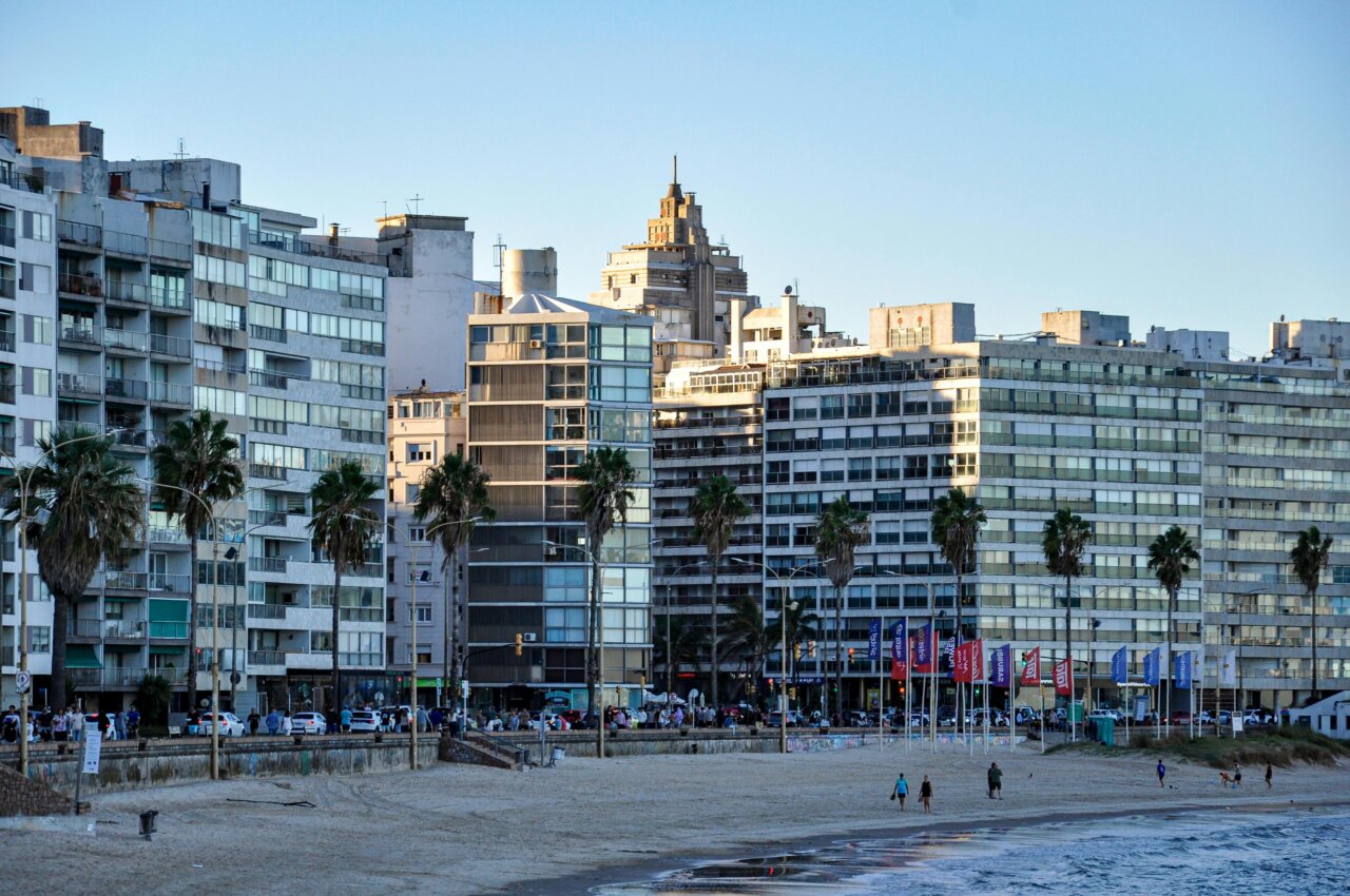 Vista de edificios en la costa con palmeras y personas caminando