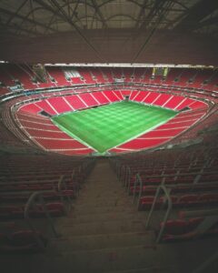Vista interior de una arena techada con asientos rojos y césped verde