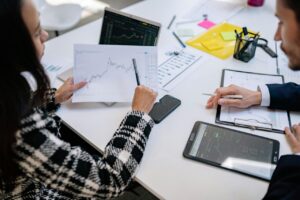 Personas analizando gráficos financieros en una reunión de trabajo