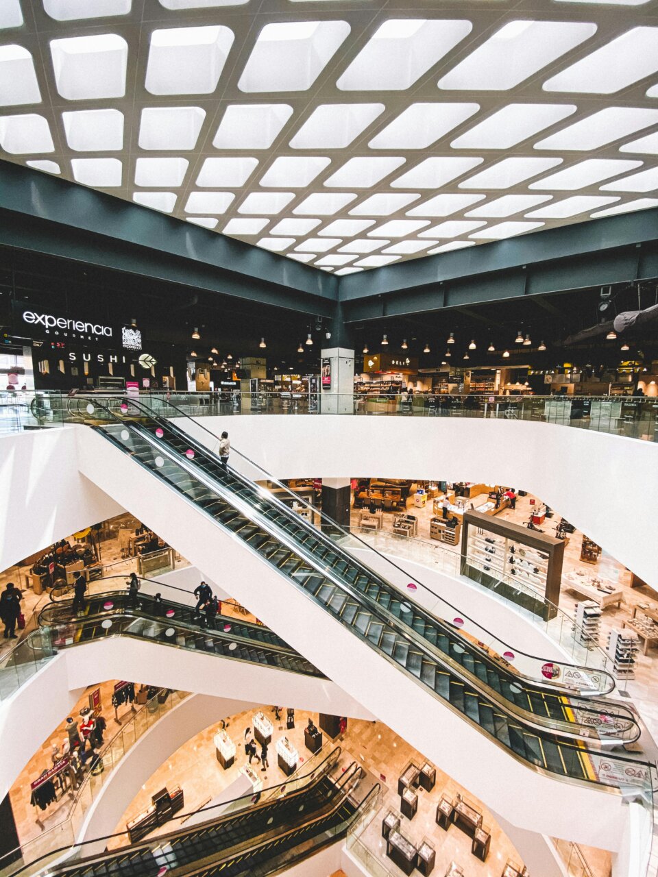 Vista interior del centro comercial con escaleras eléctricas y locales comerciales