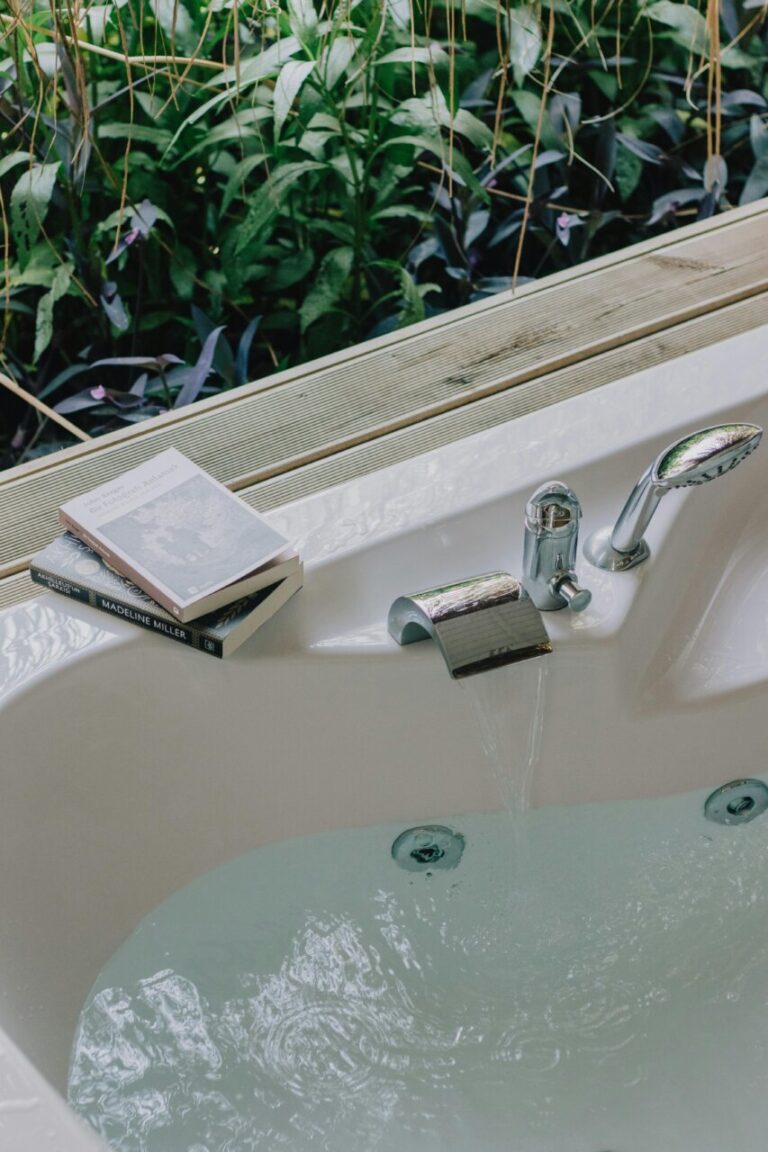Baño moderno con agua y libros sobre bienestar en un entorno natural.