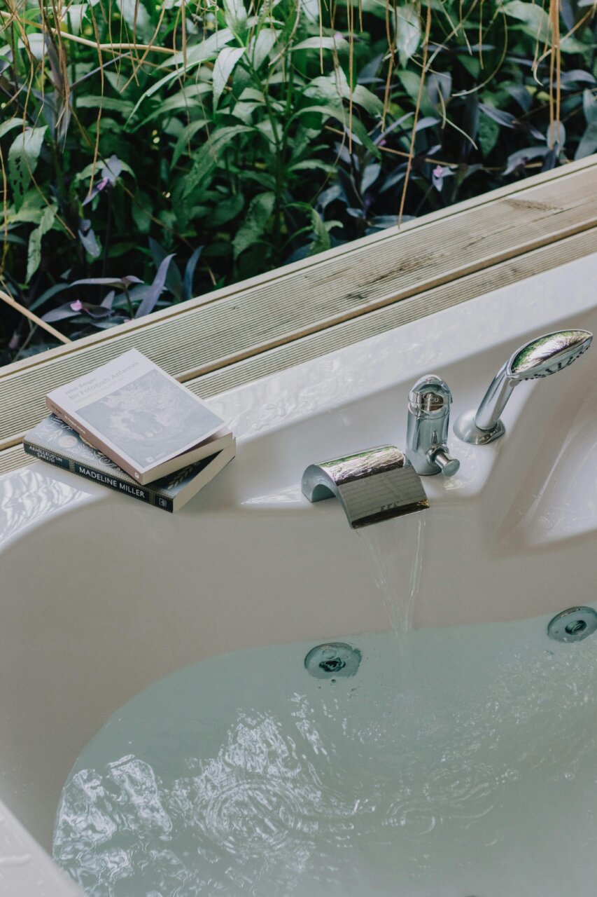 Baño moderno con agua y libros sobre bienestar en un entorno natural.