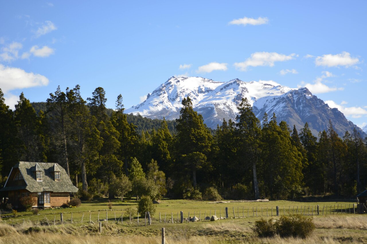 Vista panorámica de montañas nevadas y cabaña en Chubut