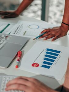 Manos sobre una mesa con gráficos y un ordenador portátil