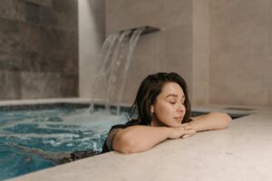 Mujer relajándose en una piscina con agua y cascada