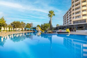 Piscina de un hotel con toboganes y palmeras en un día soleado