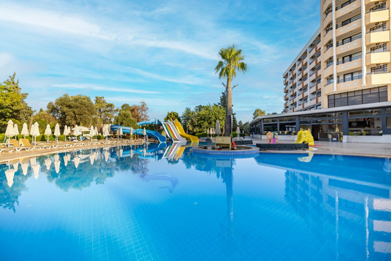 Piscina de un hotel con toboganes y palmeras en un día soleado