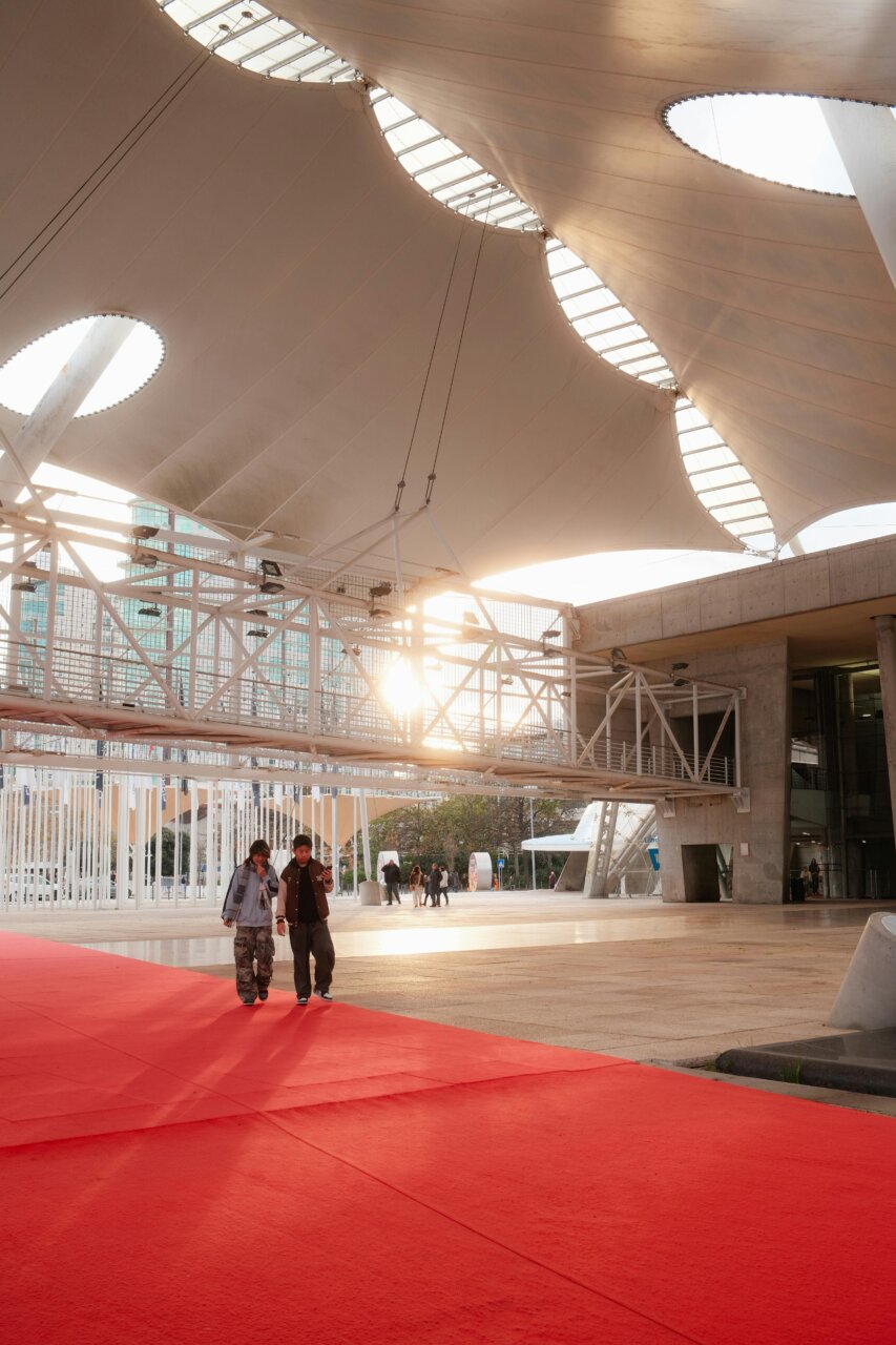 Personas caminando sobre una alfombra roja en un centro de convenciones moderno
