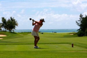 Mujer jugando golf en un campo con vista al mar
