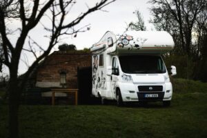 Autocaravana estacionada en un área verde junto a una construcción de ladrillo