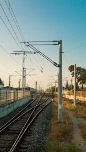 Vista de vías de tren con postes eléctricos en un entorno urbano