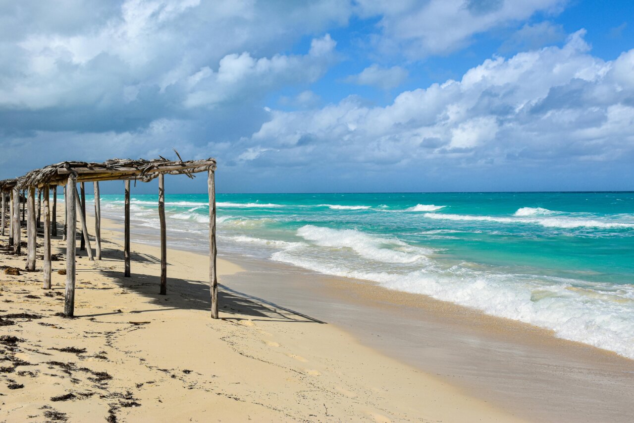 Vista de una playa con cabañas de madera y mar turquesa