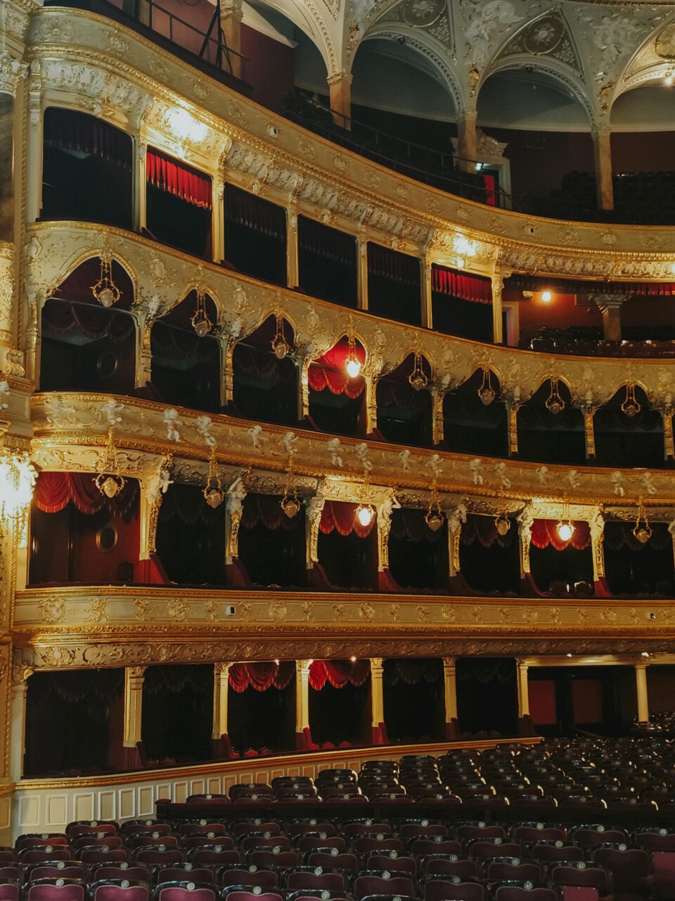 Vista interior de un teatro con asientos y decoraciones doradas
