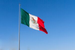 Bandera de México ondeando bajo un cielo azul claro