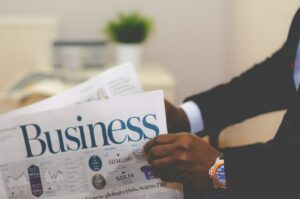 Persona leyendo un periódico sobre negocios en una oficina