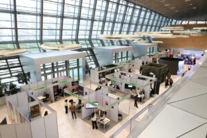 Vista aérea de un centro de exposiciones con stands y visitantes