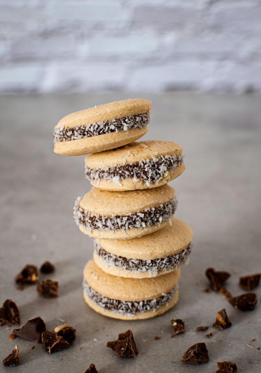 Alfajores apilados con chocolate y coco en una mesa