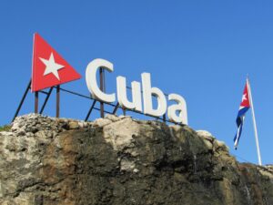Cartel que dice Cuba con bandera cubana al fondo