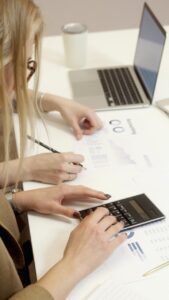 Dos personas trabajando en un proyecto de inversión con calculadora y laptop