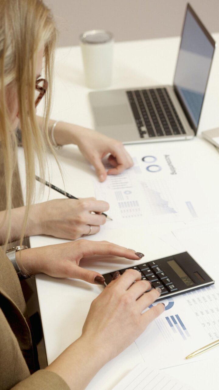 Dos personas trabajando en un proyecto de inversión con calculadora y laptop