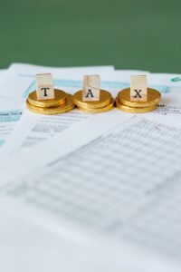 Monedas doradas con letras que forman la palabra TAX sobre documentos fiscales