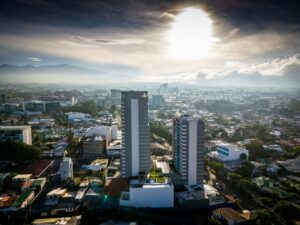 Vista aérea de edificios en una ciudad costarricense con montañas al fondo.