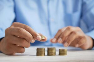Persona organizando monedas en pilas sobre una mesa