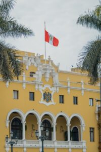 Edificio amarillo con bandera de Perú y palmeras en primer plano
