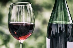 Copa de vino tinto junto a una botella en un fondo natural
