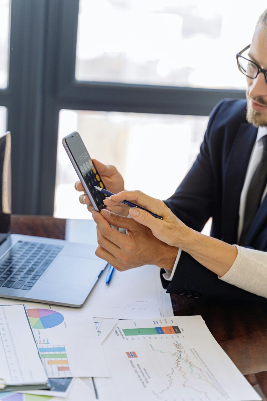 Dos personas revisando datos en un teléfono móvil y documentos en una mesa